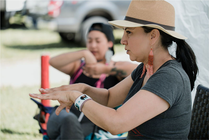 Dr. Belinda kakiyosēw Daniels, pictured sitting and gesturing with hands.