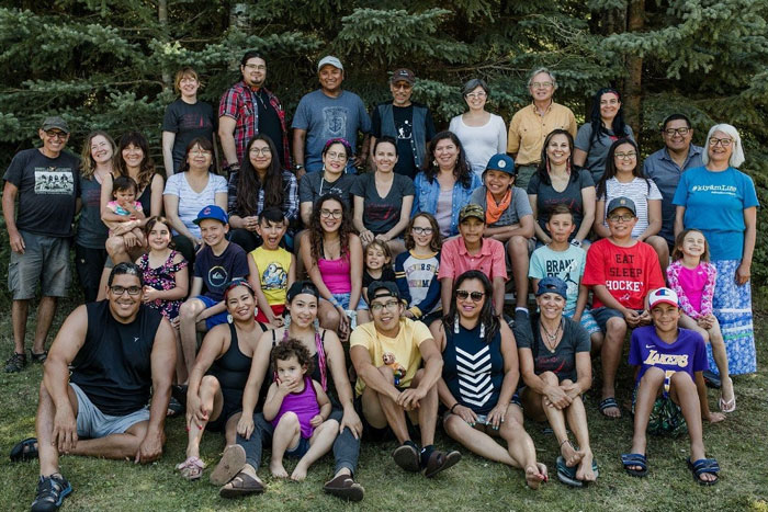 A group of language learners pictured together outside in front of trees during a summer language camp.