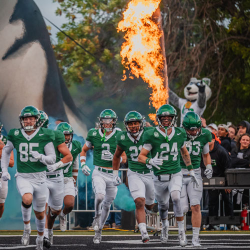 USask Huskie football team coming onto field with flames behind them
