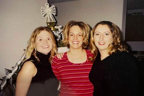 Three women smiling with their arms over each other's shoulders
